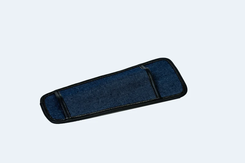The Ambutech Mobility Cane Holster in blue denim, lying flat: a long, flat V-shaped open pocket with black piping around its edges and a black strap divider across its face; the pocket is open at the top and tapered toward the bottom, and a belt loop and clip sit on its back side.